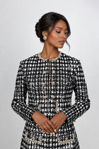 A woman wearing a black and white tweed jacket with gold buttons and pearl trim, old money classic style