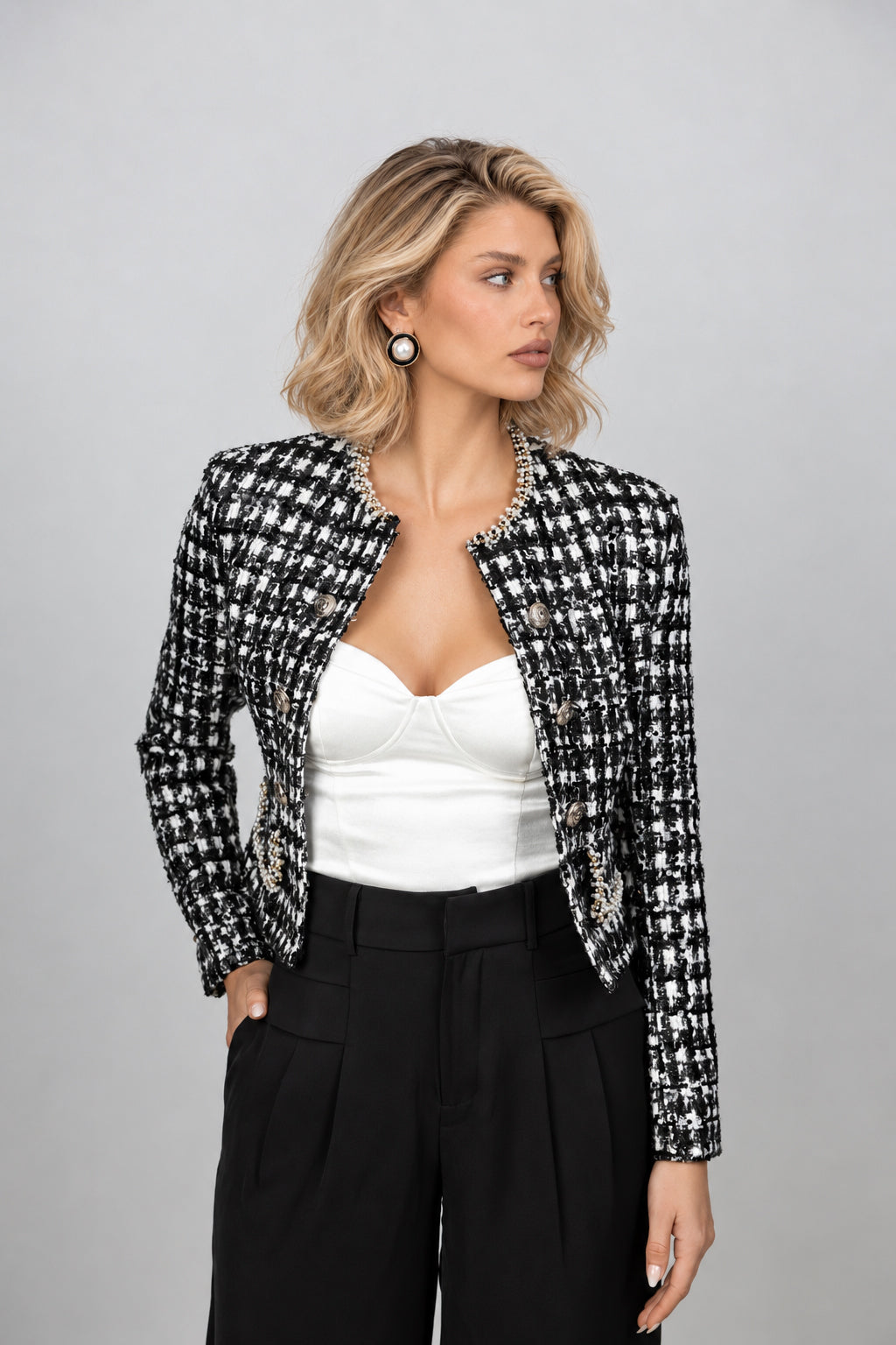 A woman in an elegant black and white houndstooth tweed cropped jacket, old money style