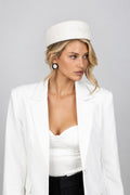 A woman wearing a white wool pillbox hat with a signature CÈGLÈ logo 