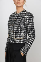 woman wearing a black and white elegant, classic tweed jacket , long sleeves, and a pearl trim neckline