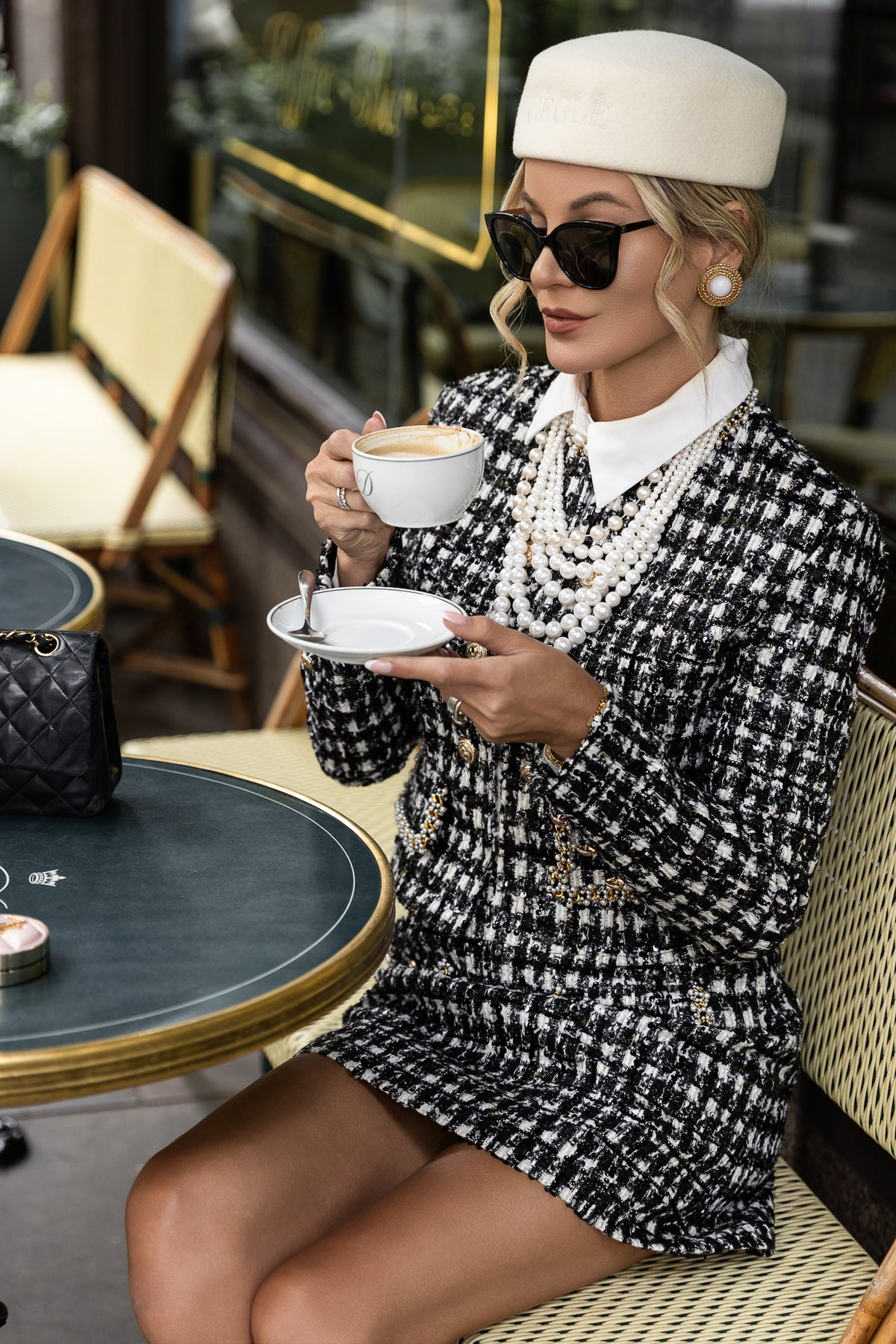 Woman wearing CÈGLÈ black and white tweed blazer and matching mini skirt with white wool pillbox hat in an elegant old money inspired look