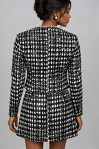 A woman shown from the back wearing a black and white tweed blazer and skirt set 