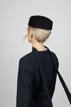 A woman wearing a black wool pillbox hat and black blazer