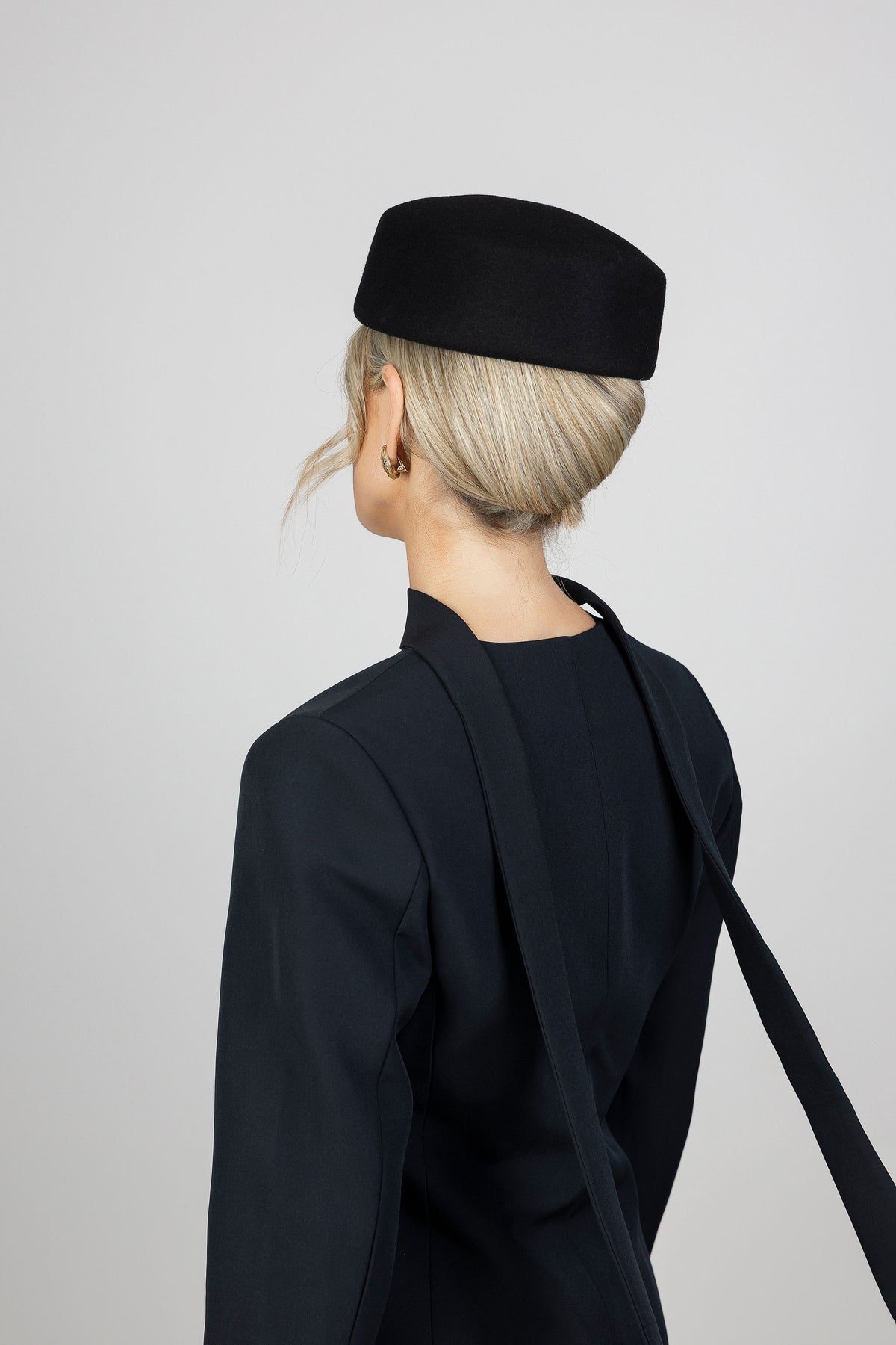 A woman wearing a black wool pillbox hat and black blazer